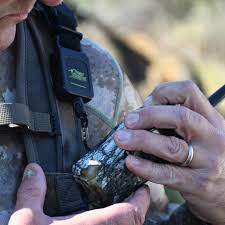 Jager die zijn portofoon aan een Gearkeeper retractor aan zijn camouflage uitrusting heeft bevestigd